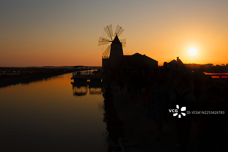 日落时分湖边传统风车和建筑的剪影，橙色天空，意大利马尔萨拉，La Finestra Sul Sale图片素材
