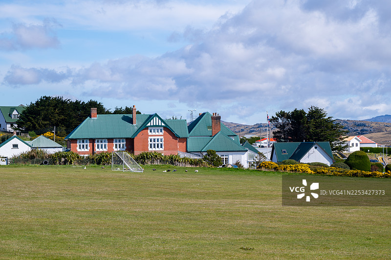 绿顶房屋和足球门在多云天空下的草地上图片素材