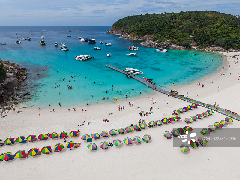 繁忙的热带海滩，有着码头和色彩缤纷的遮阳伞图片素材