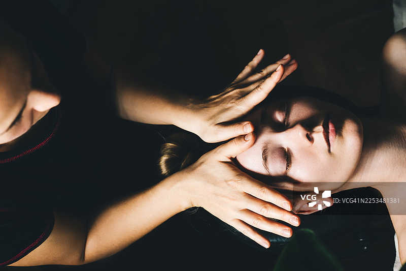 特写镜头，展示一次放松的面部按摩，温柔的手支撑着客户的面部，她闭着眼睛休息。图片素材