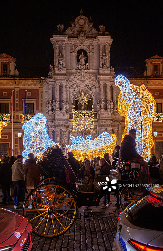 人们在塞维利亚圣特尔莫宫前拍摄灯光璀璨的耶稣诞生场景图片素材