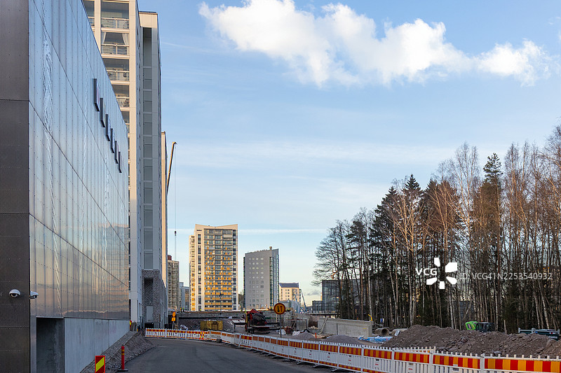 蓝天白云下的现代建筑旁空旷的道路，附近有森林和建筑工地，芬兰埃斯波，芬诺图片素材