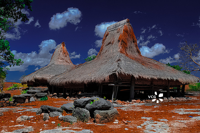 茅草屋顶的传统房屋，背景是戏剧性的多云蓝天，展示了原住民建筑，印度尼西亚，瓦因加普图片素材