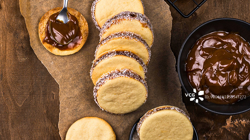 质朴的木桌上摆放着美味的阿法赫饼，淋有阿法赫酱并撒上椰蓉，俯视角度拍摄图片素材