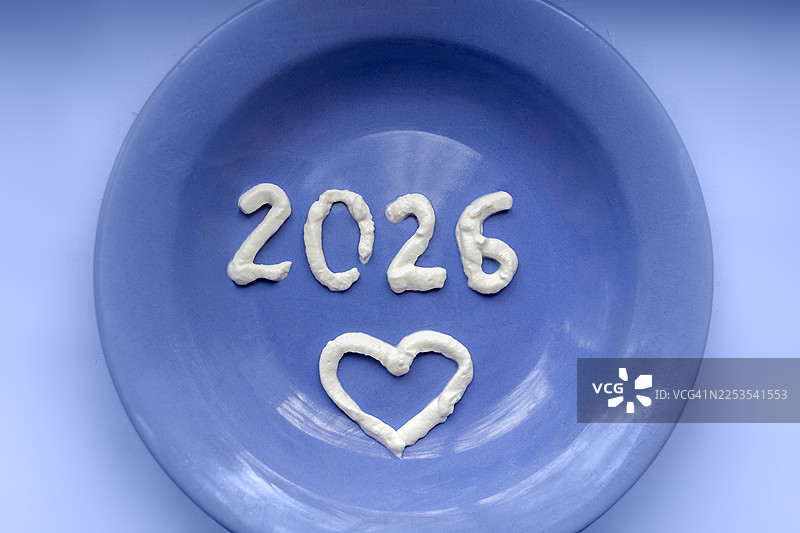 蓝盘上用奶油写着2026年和心形图案图片素材