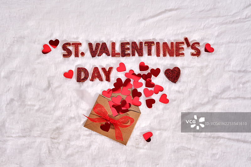 情人节主题，信封里漏出心形纸屑，背景是白色毛绒毯子图片素材