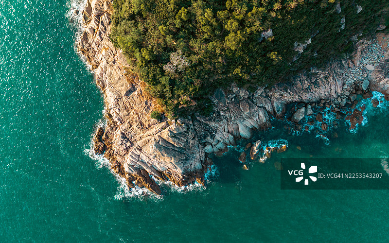 从空中俯瞰，崎岖、树木繁茂的海岸线与清澈碧绿的海水相遇图片素材