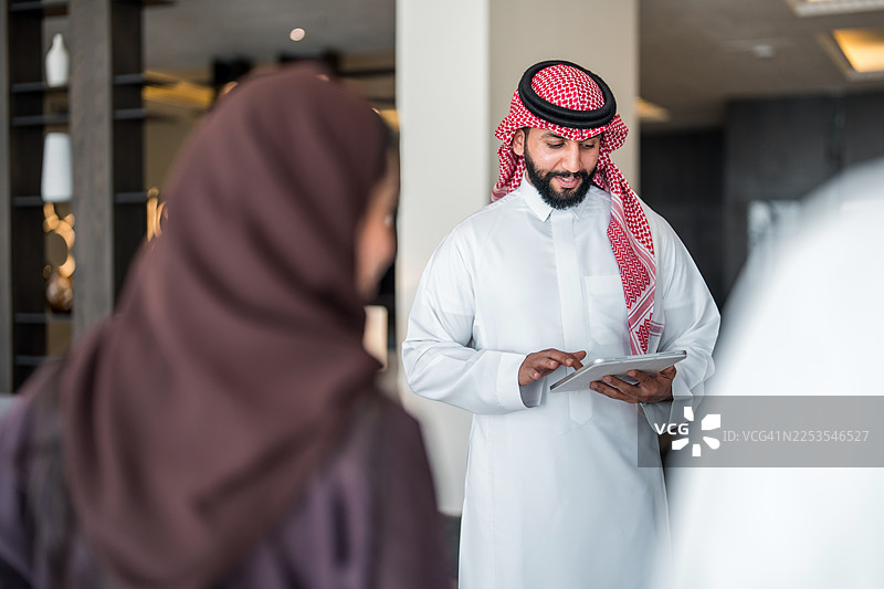 中年阿拉伯经理以友善的手势欢迎夫妇图片素材