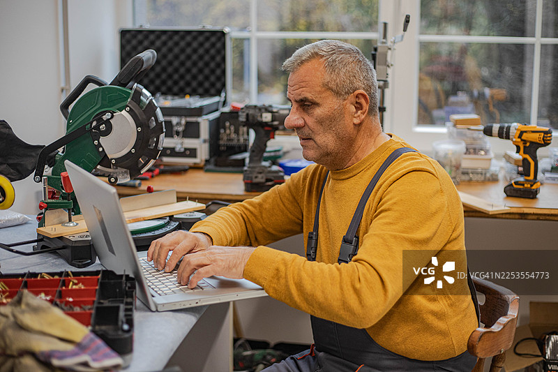 工匠在工作室里工作，用笔记本电脑支撑身体图片素材