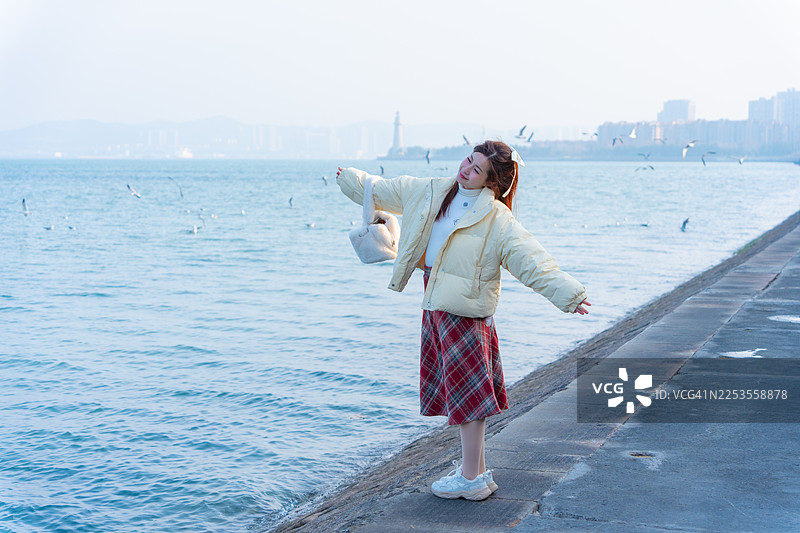一位美丽的女子正在欣赏中国海岸附近的威海市的壮丽景色。图片素材