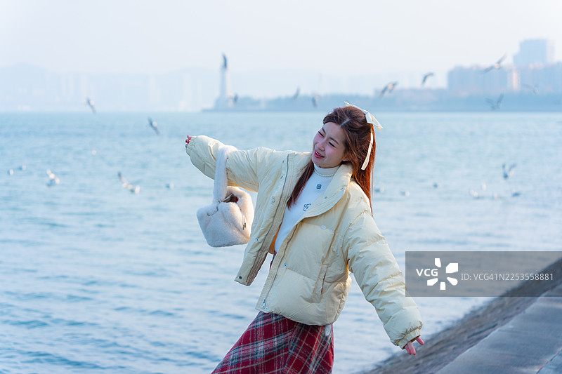 一位迷人的女士站在威海海滩前，欣赏着这座城市附近的美丽海滩。图片素材