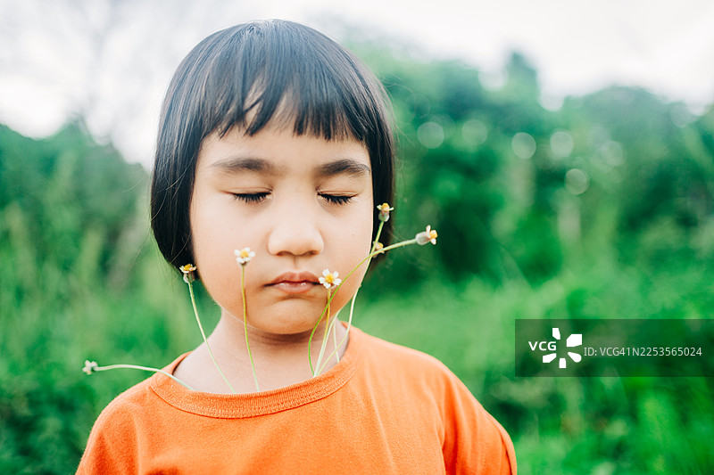 一个小女孩的特写肖像，她的衬衫里长出了植物图片素材