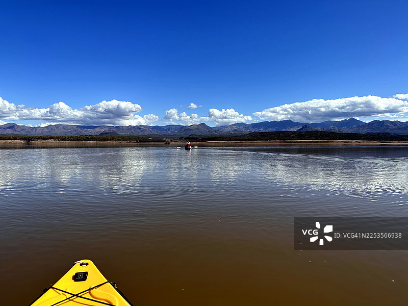 蓝天下，白云朵朵，一艘黄色皮划艇在前景，远处是山峦，人们在宽阔的湖面上划皮划艇，美国，美国，马蹄湖图片素材