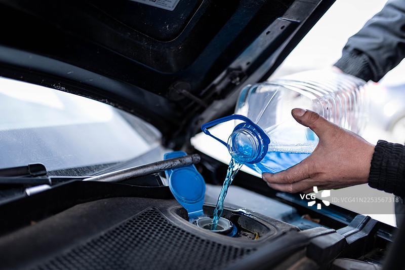 特写：男子正在检查并为汽车添加防冻液图片素材