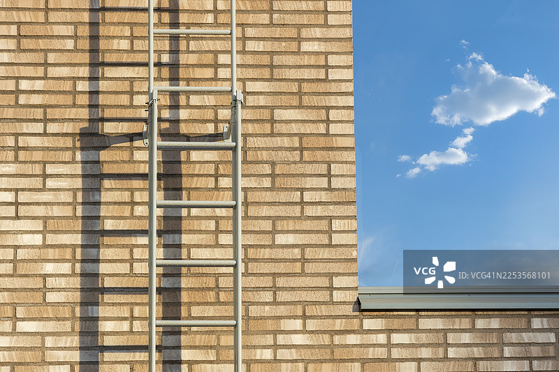 仰视砖砌建筑，侧面有金属梯子，背景是蓝天白云，芬兰图片素材