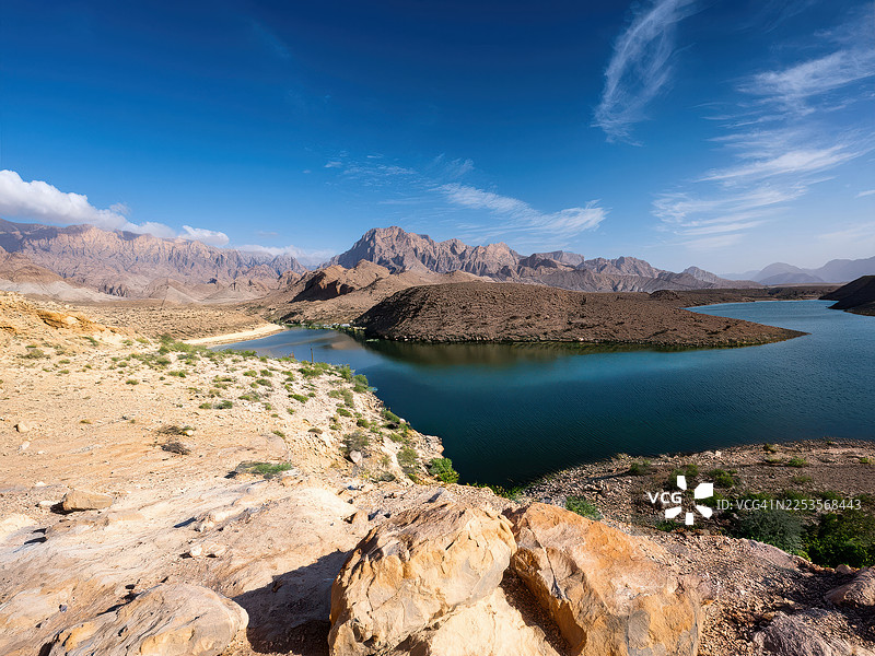 阿曼塞拉莱，崎岖群山环抱下的宁静湖泊，在晴朗蓝天下，景色优美图片素材