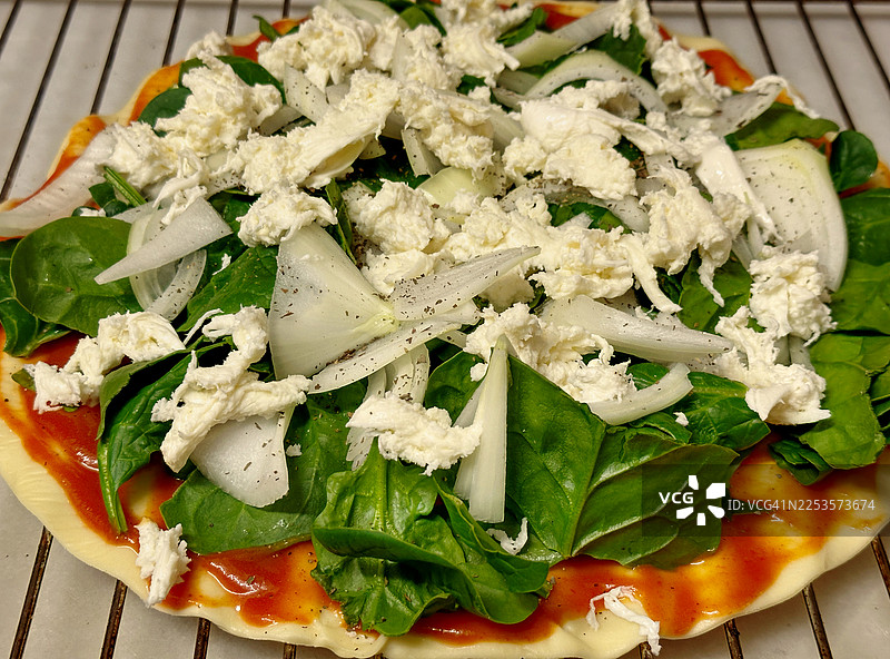 准备烘烤的比萨，配有番茄、菠菜、洋葱和马苏里拉奶酪图片素材