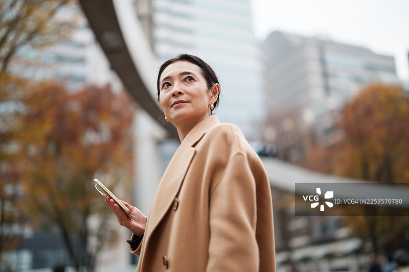 一位自信的女商人在市中心区边走边使用智能手机图片素材