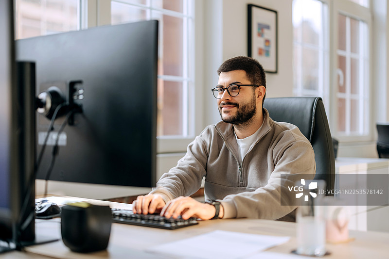 穿着休闲的男士在办公室使用电脑工作图片素材