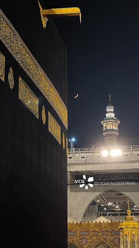 从低角度拍摄的麦加克尔白天鹅清真寺和宣礼塔，背景是夜空和新月，位于沙特阿拉伯麦加。图片素材