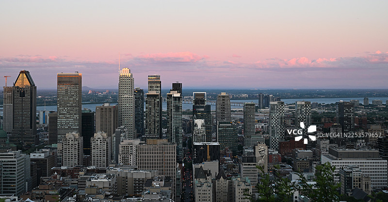 加拿大日落时分充满活力的城市天际线鸟瞰图，展现了现代建筑、河流和色彩斑斓的天空图片素材