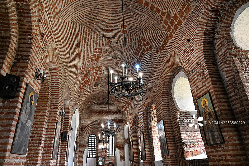 保加利亚一座历史悠久的砖砌教堂内部的低角度视图，拥有拱形天花板和吊灯图片素材