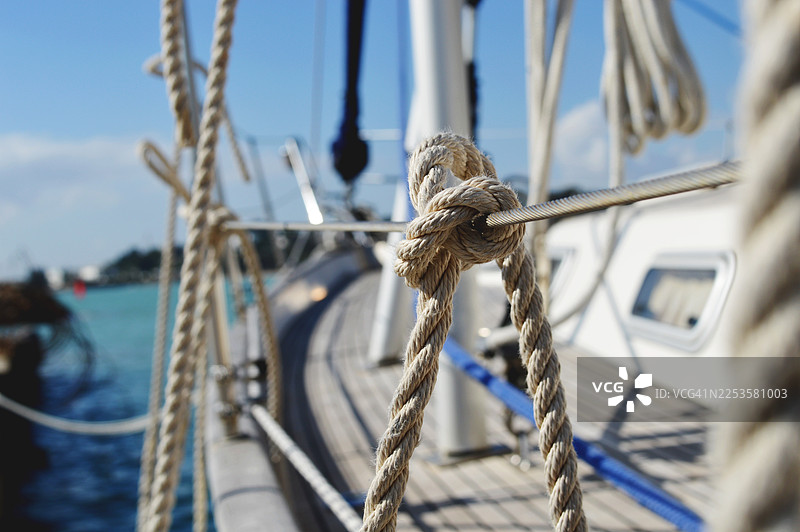 帆船甲板上绳结的特写，背景是绿松石色的海水和蓝天图片素材