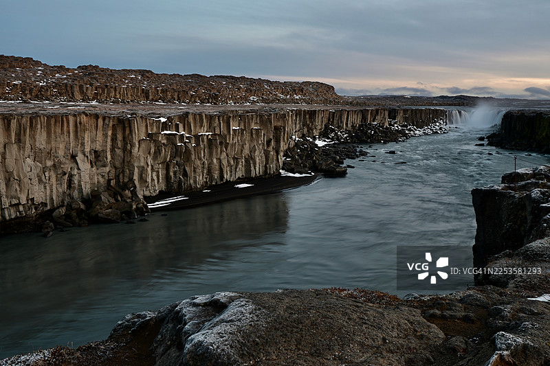 冰岛，冬季，戏剧性的峡谷瀑布，覆雪的玄武岩柱，阴天图片素材