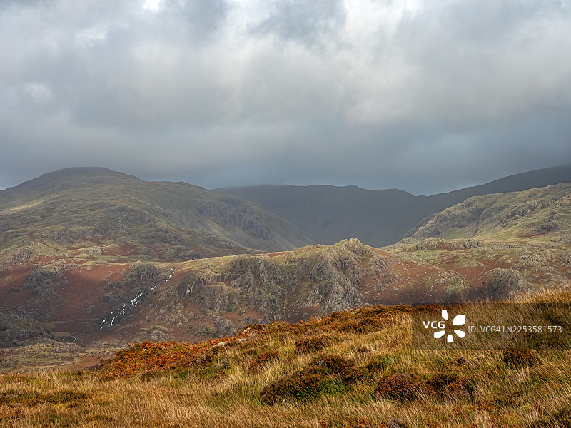 英国，英国，西斯韦特费尔斯，云雾缭绕、充满氛围的天空下，展现着崎岖地貌和远处瀑布的戏剧性山地景观图片素材