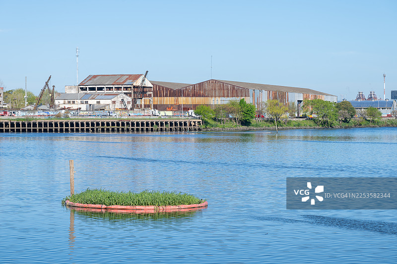 阿根廷布宜诺斯艾利斯，河畔的工业建筑和漂浮花园构成一幅美景，天空湛蓝图片素材