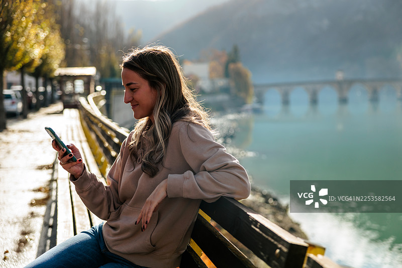 女人在河边使用智能手机放松图片素材