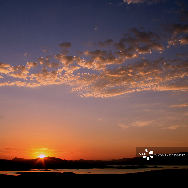 日落时分，剪影风景映衬着鲜艳的天空，云彩在水面上反射着温暖的光芒，美国博尔德城，米德湖国家休闲区图片素材