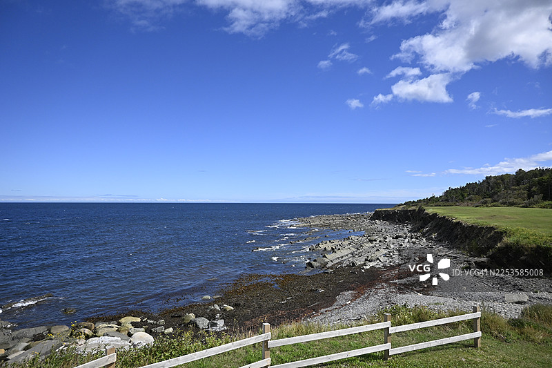 里穆斯基，加拿大，晴朗天空点缀着几朵云彩，岩石海岸与深邃的蓝色大海交汇，展现出自然之美与宁静的风景。图片素材