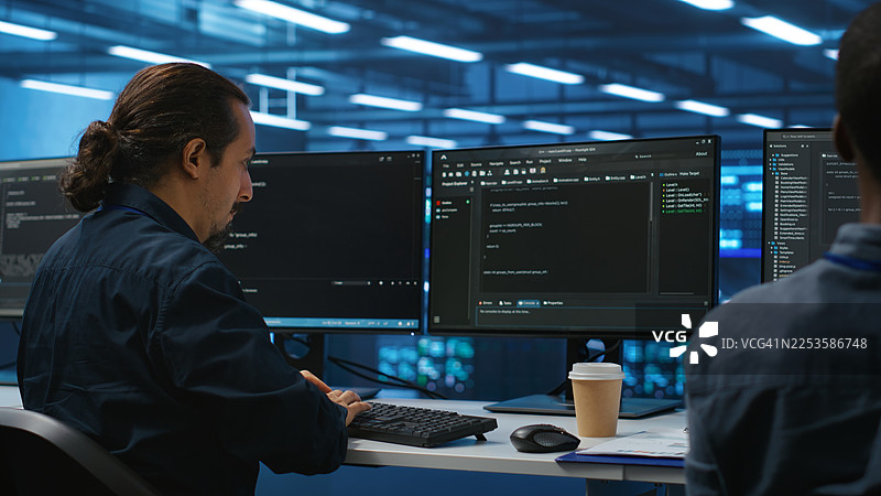IT工程师在办公室加班，在屏幕显示代码的情况下敲击键盘图片素材