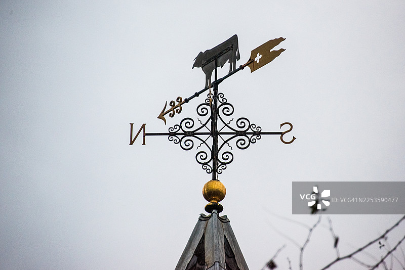 牛造型风向标剪影，背景是灰色的天空图片素材