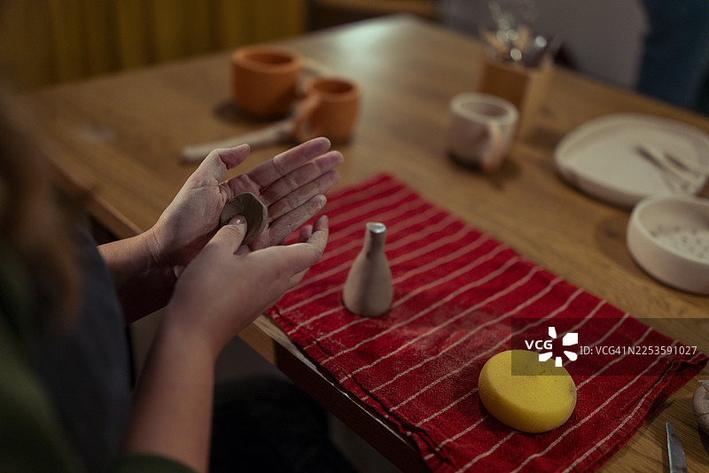 一位看不清面容的女性正用双手塑造一小块锥形陶土图片素材