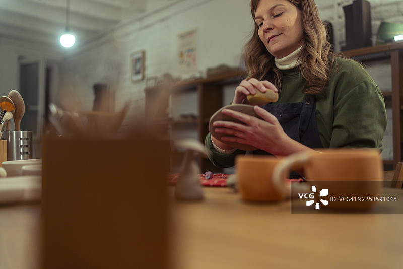 一位专注的女陶艺师在她的陶艺工作室里塑造盘子图片素材