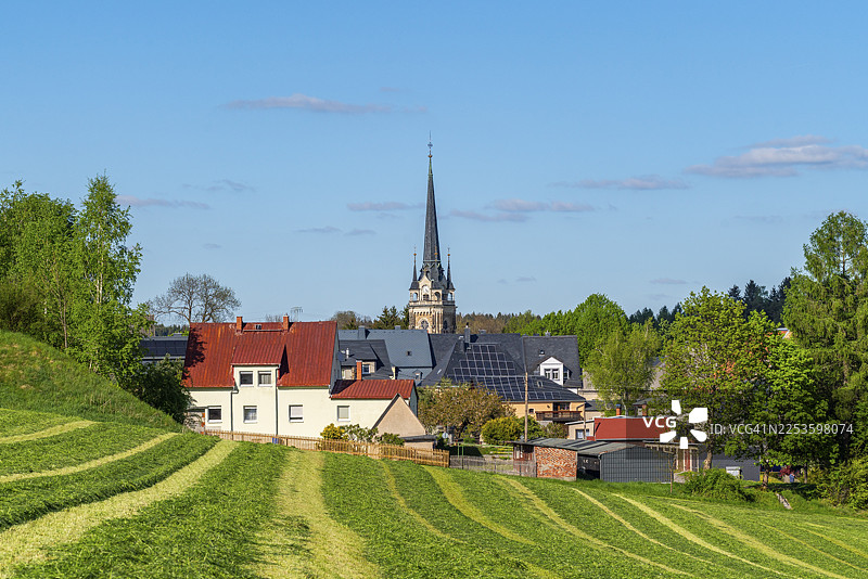从一片修剪过的田野望去，可以看到萨克森州厄尔茨山脉小镇埃尔特尔莱因的圣劳伦斯教堂和房屋图片素材