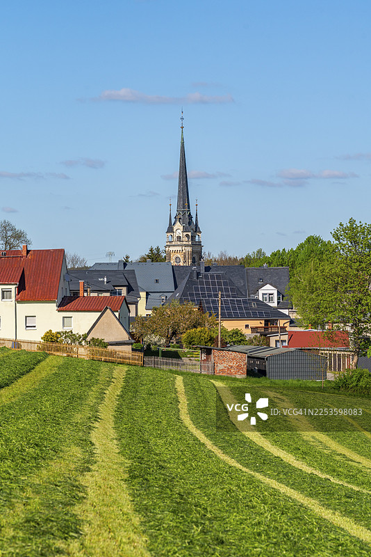 萨克森州厄尔茨山脉小镇埃尔特尔莱因，圣劳伦斯教堂及房屋，从一片修剪过的田野望去图片素材