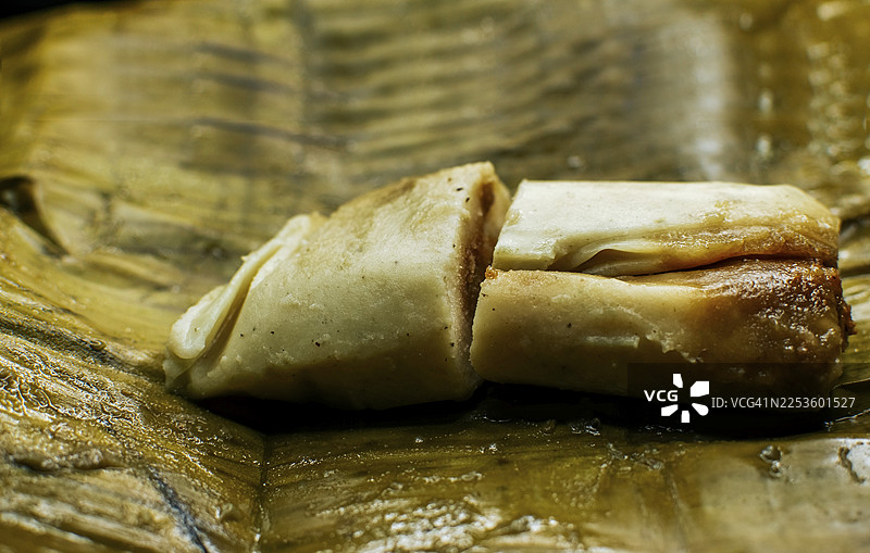 特写镜头，香蕉叶上的传统玉米粽。尼加拉瓜 pisque 玉米粽放在香蕉叶上。Tamalpisque 是中美洲的传统食物，一种塞满馅料的玉米粽，用香蕉叶包裹着食用。图片素材