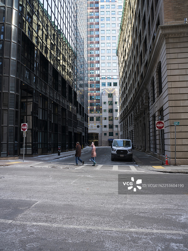 冬天，两个人在波士顿市中心的街道上过马路图片素材