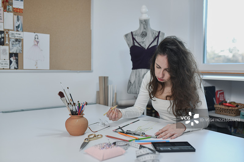 创意裁缝在明亮的服装工作室里绘制时装草图图片素材