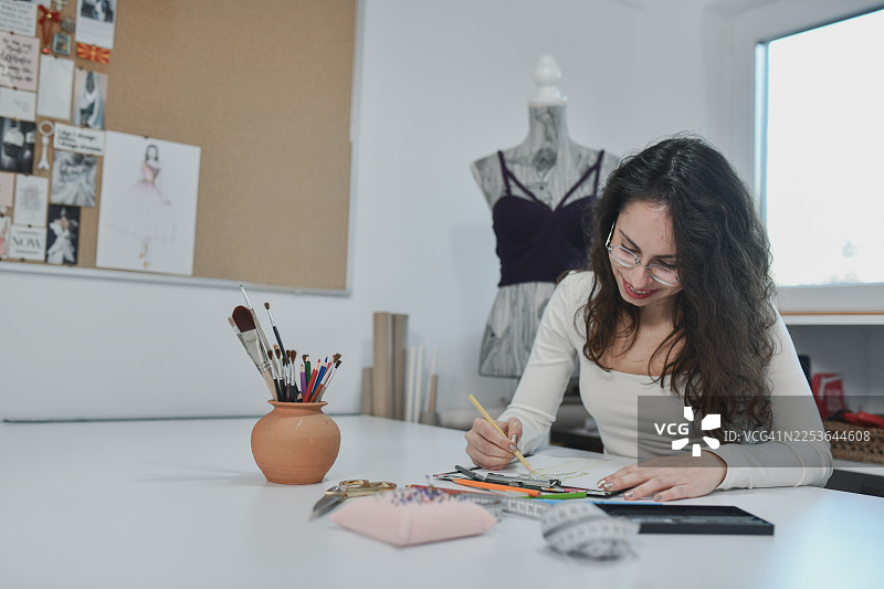 时装设计师专注于时装草图的工作室场景图片素材