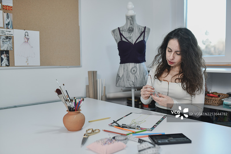 现代裁缝在工作室休息并擦拭眼镜图片素材