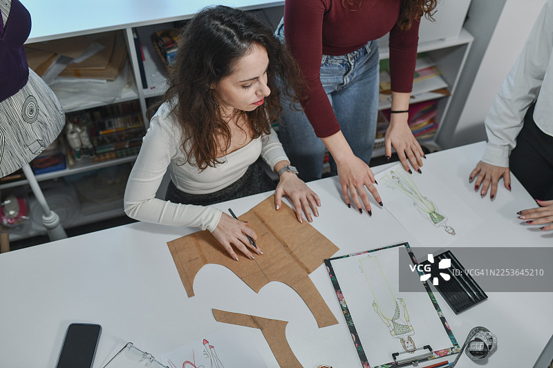 一群朋友在明亮的服装工作室里合作进行服装制作和时尚设计项目图片素材