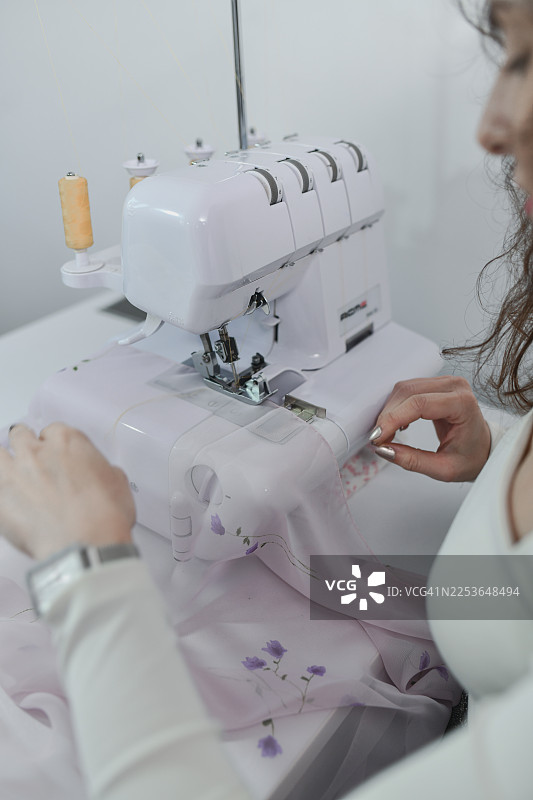 设计师用粉色面料和缝纫机制作定制服装图片素材