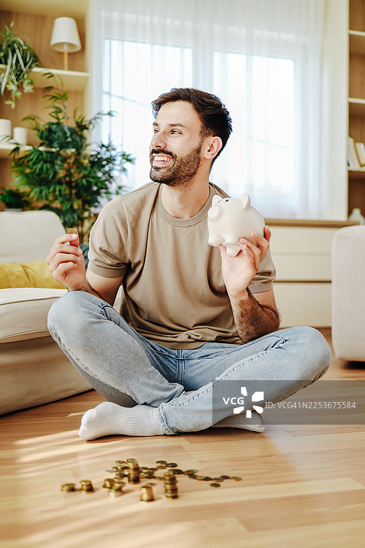 男人把钱存入储蓄罐以进行未来规划图片素材