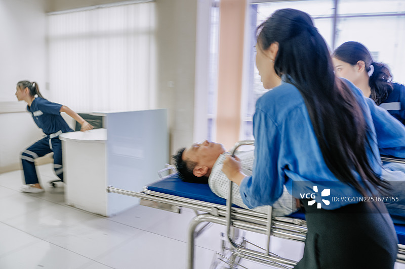 亚洲女护士和亚洲女护理员在医院走廊里用担架推着亚洲男患者图片素材