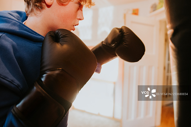 一个孩子在房间里使用沙袋和拳击手套图片素材