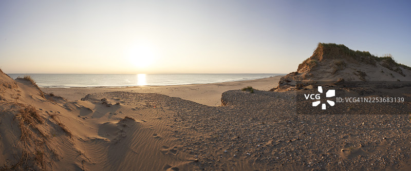 日落时分，平坦的岩石高原旁是沙丘图片素材